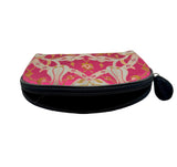 A zippered cosmetic pouch with a pink and gold patterned fabric top and a black zipper and black tassel pull, photographed on a plain light background.
