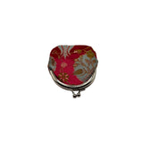 A small fabric coin purse with a red and gold floral patterned lining and a silver-tone metal clasp, shown on a plain light gray background.